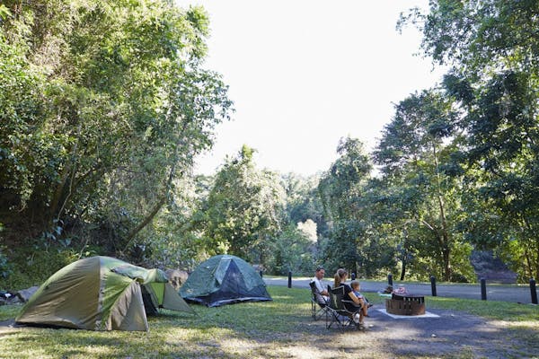 Family sitting around fir ring with tents set up in the background.