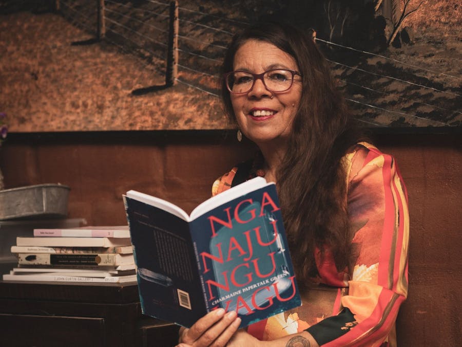 Charmaine Papertalk Green holding a copy of her anthology in front of a brown background