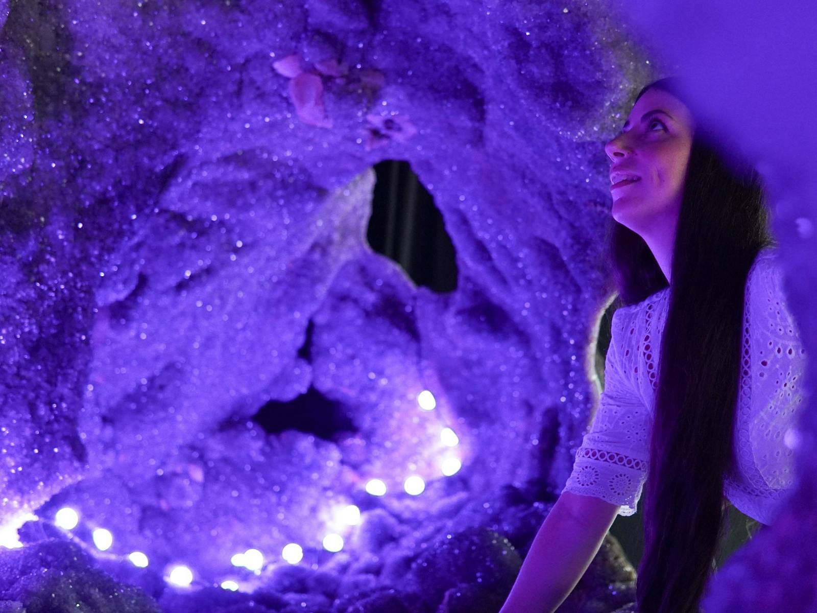 A woman looking inside the Enchanted Cave, the worlds largest amethyst geode weighing 20 tonne
