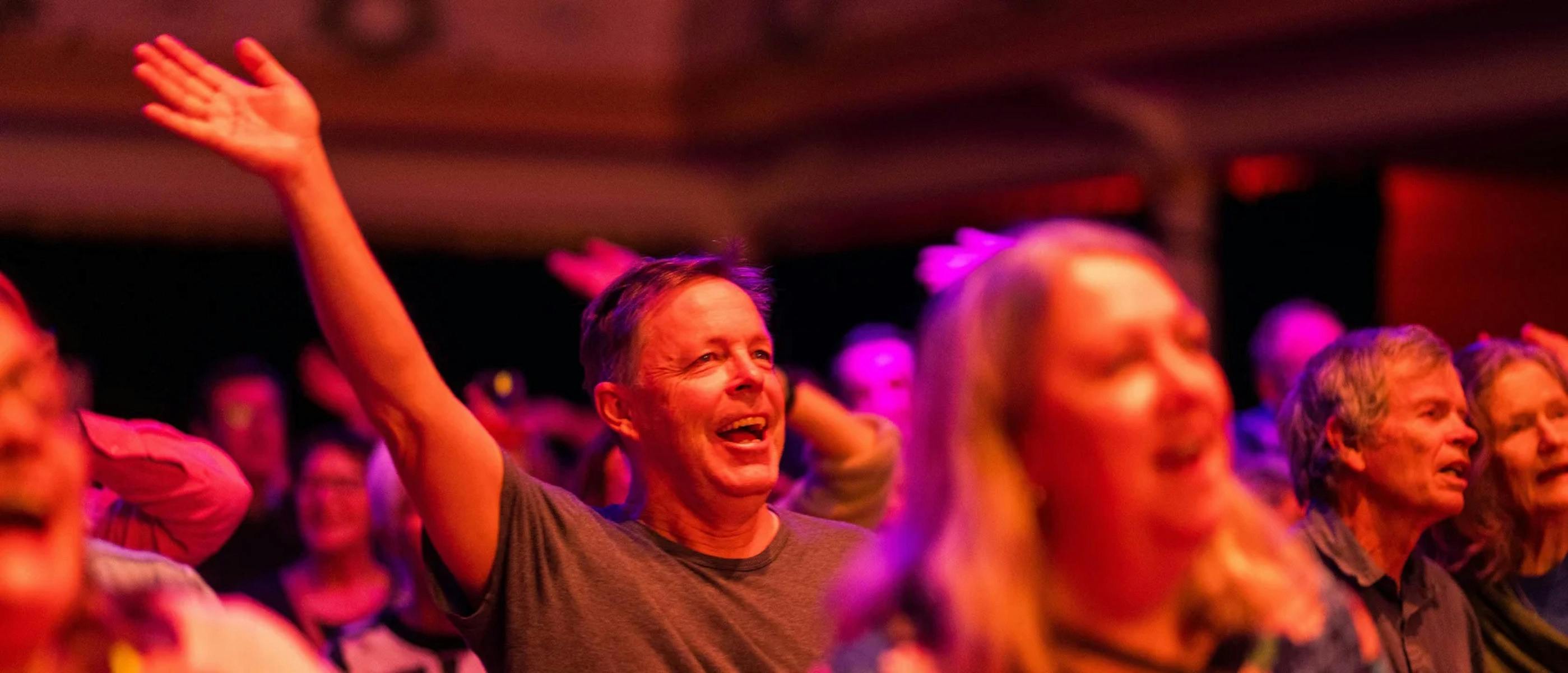 A close-up photo of a man and woman singing with other singers around