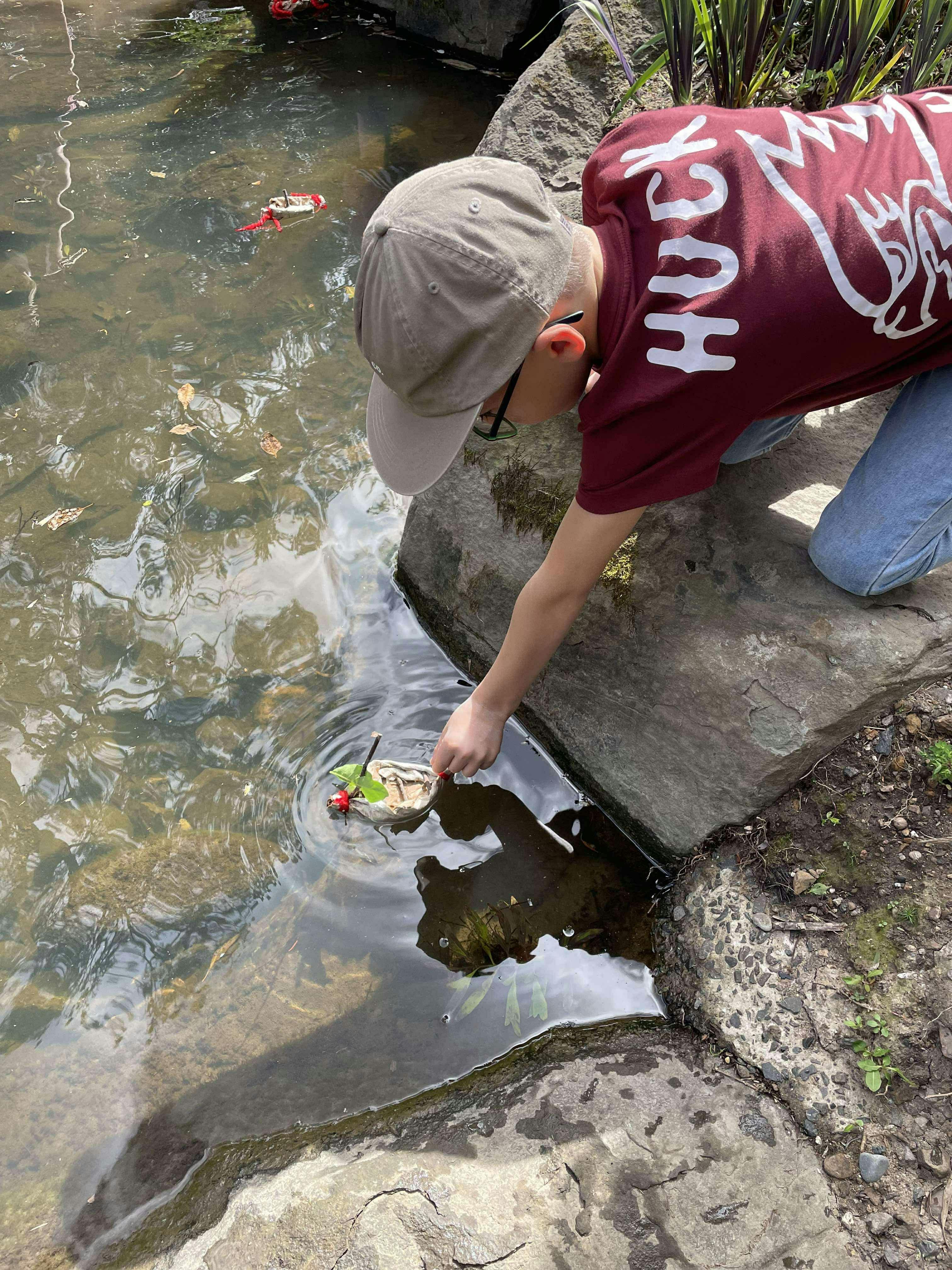 child putting mini watercraft in water