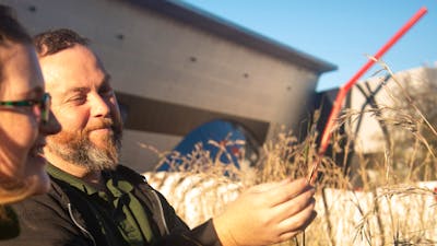 Adam Shipp smiles as he holds native grasses outdoors during a guided cultural experience.