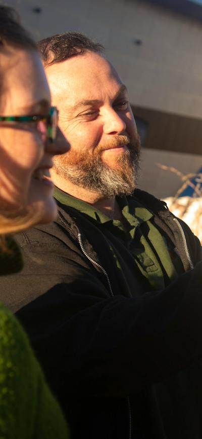 Adam Shipp smiles as he holds native grasses outdoors during a guided cultural experience.