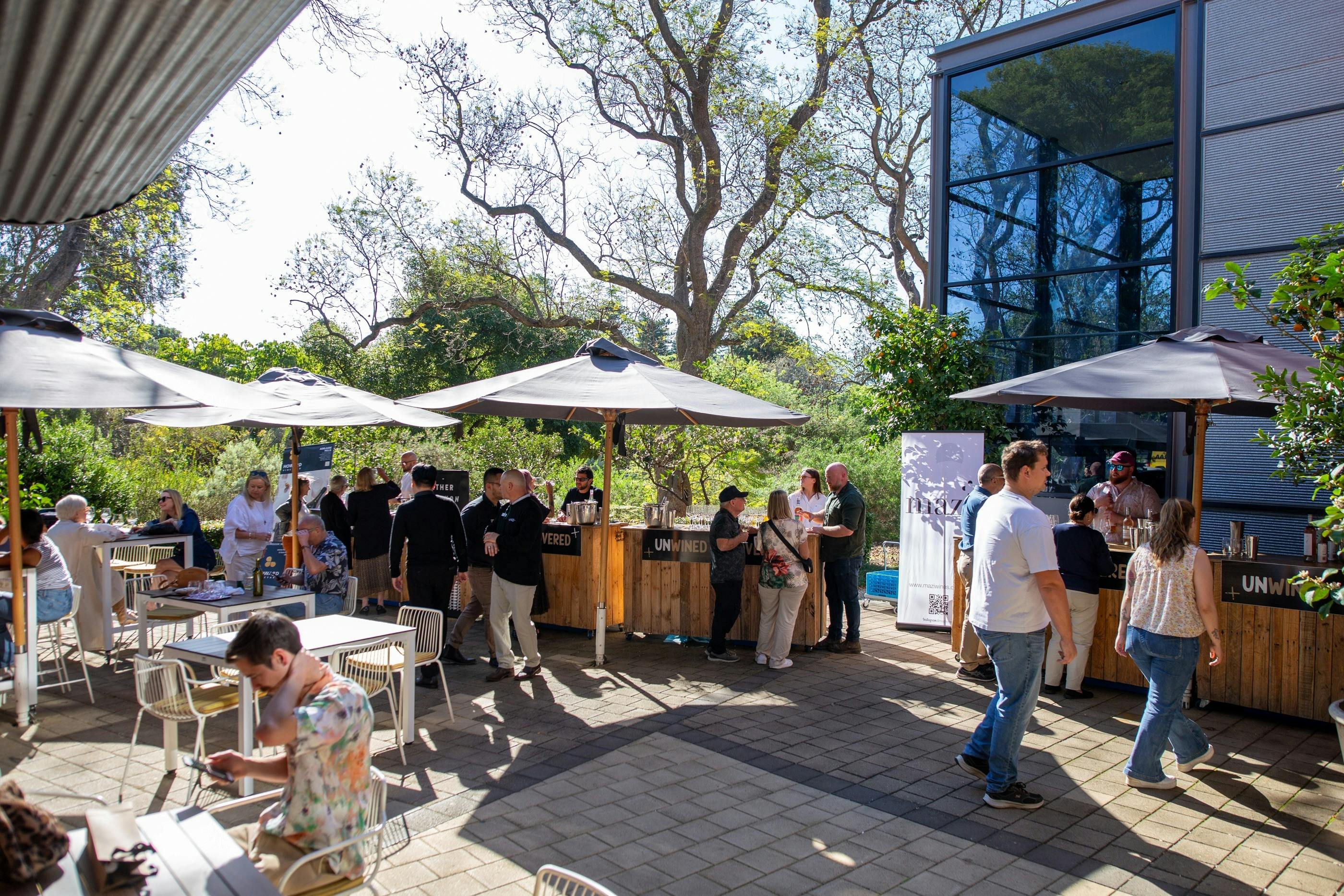 An outdoor terrace area with people tasting wines from several stalls