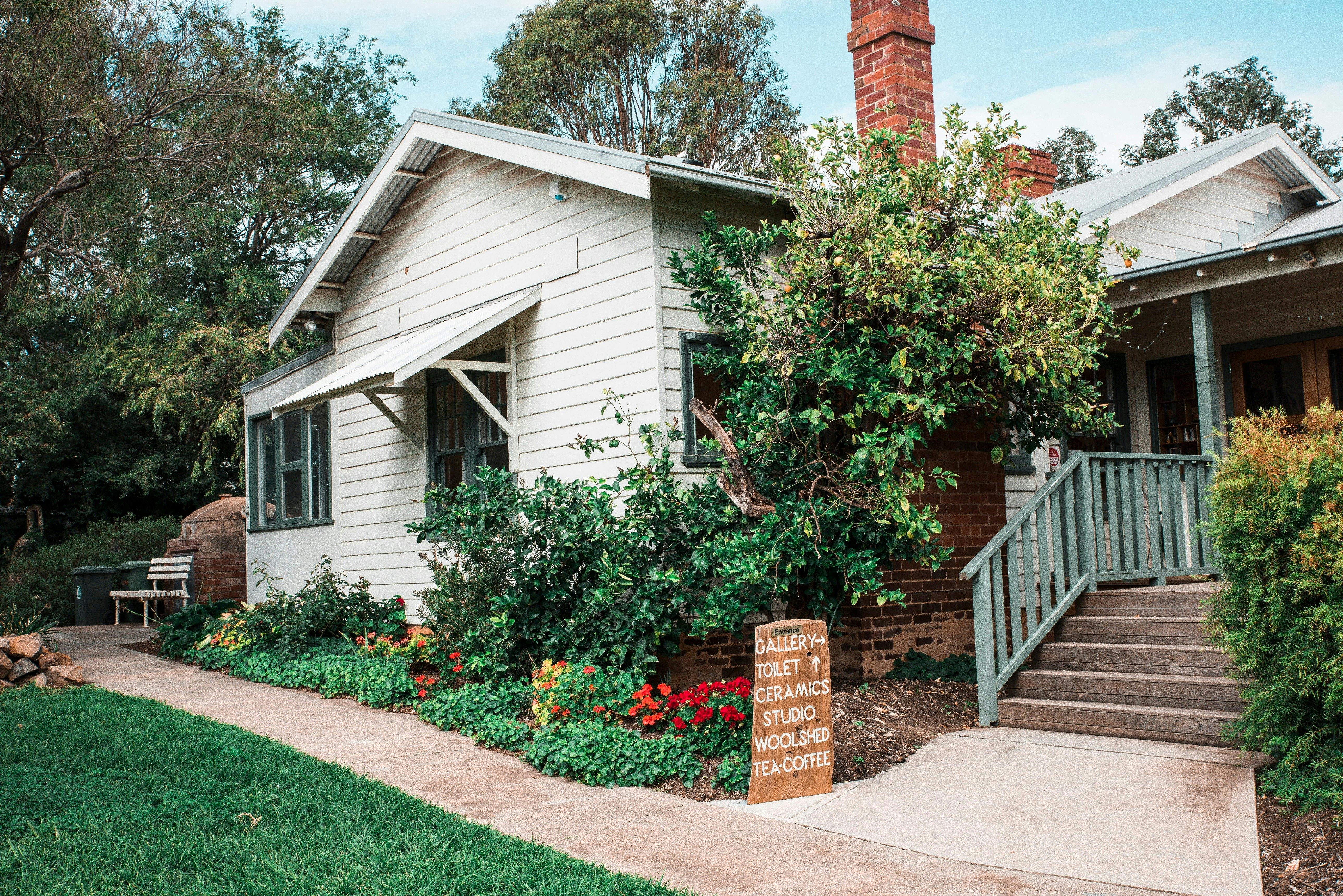 A white weatherboard house surrounded by gardens.
