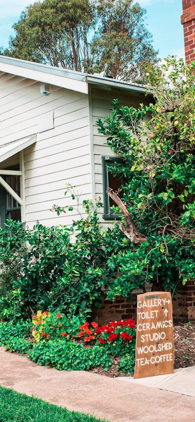A white weatherboard house surrounded by gardens.