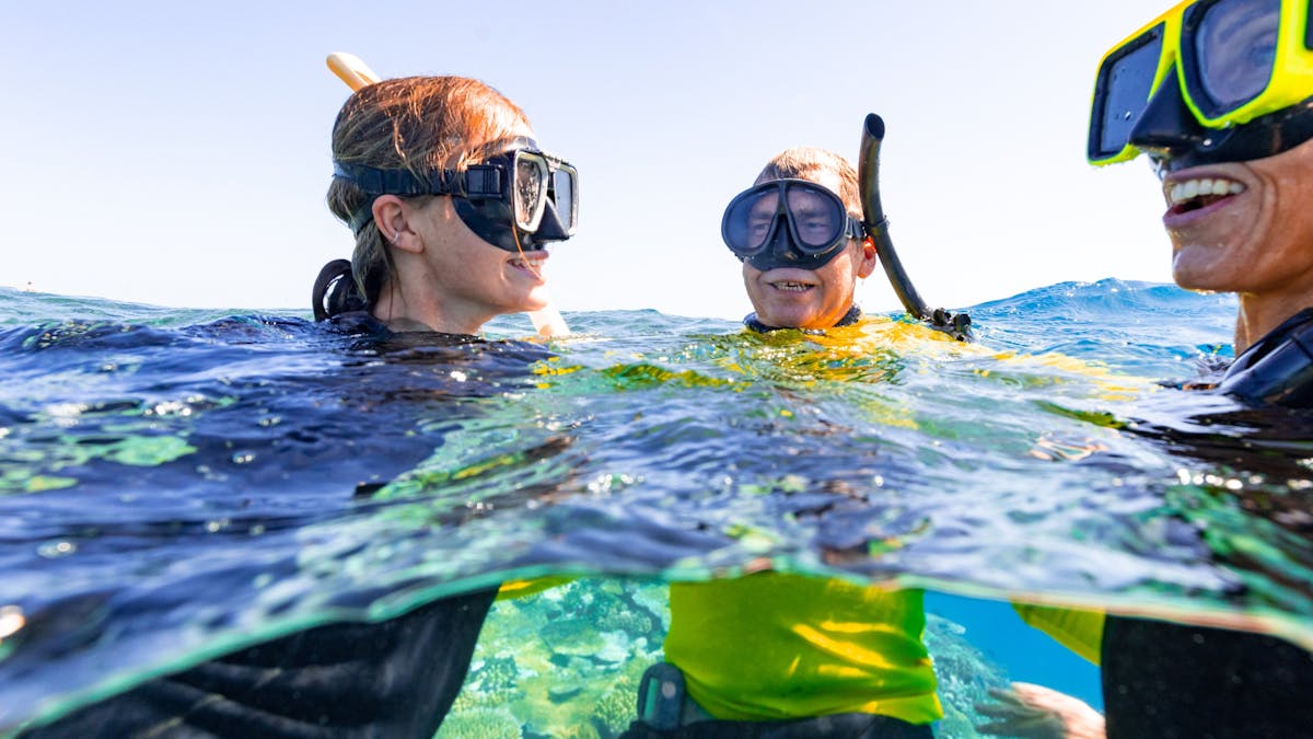 Our Master Reef Guide with two snorkelling guests laughing on the waters surface..