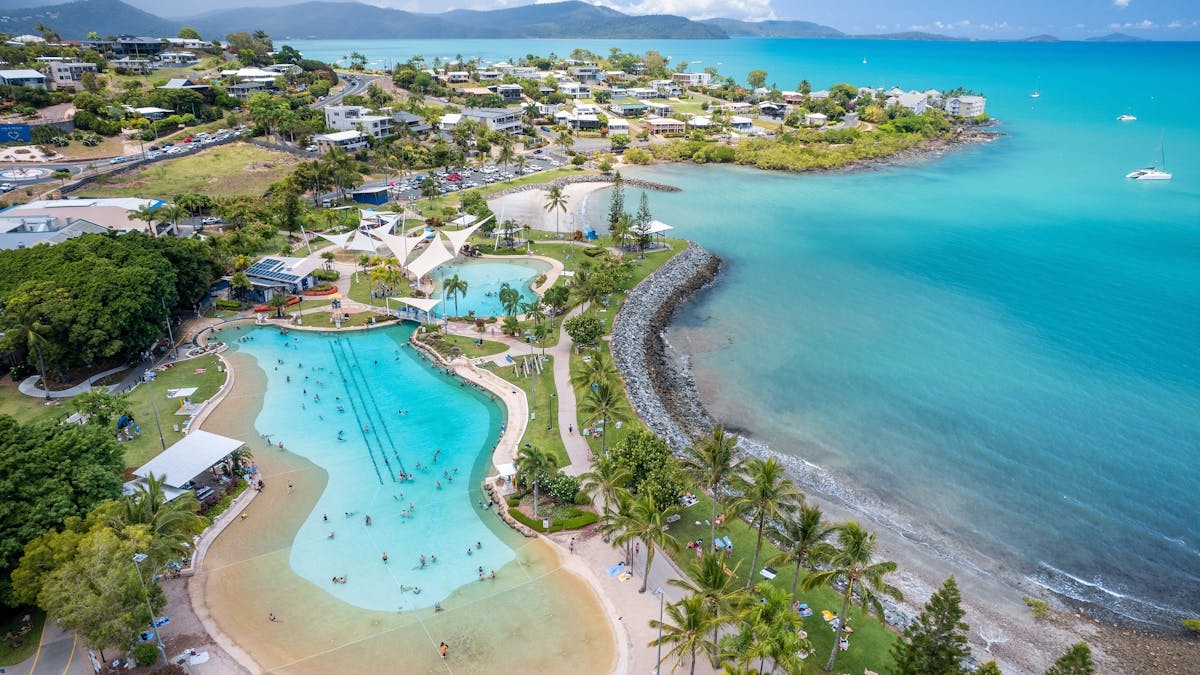 Aerial photo of Airlie Beach Lagoon with houses, beach and blue ocean surrounding