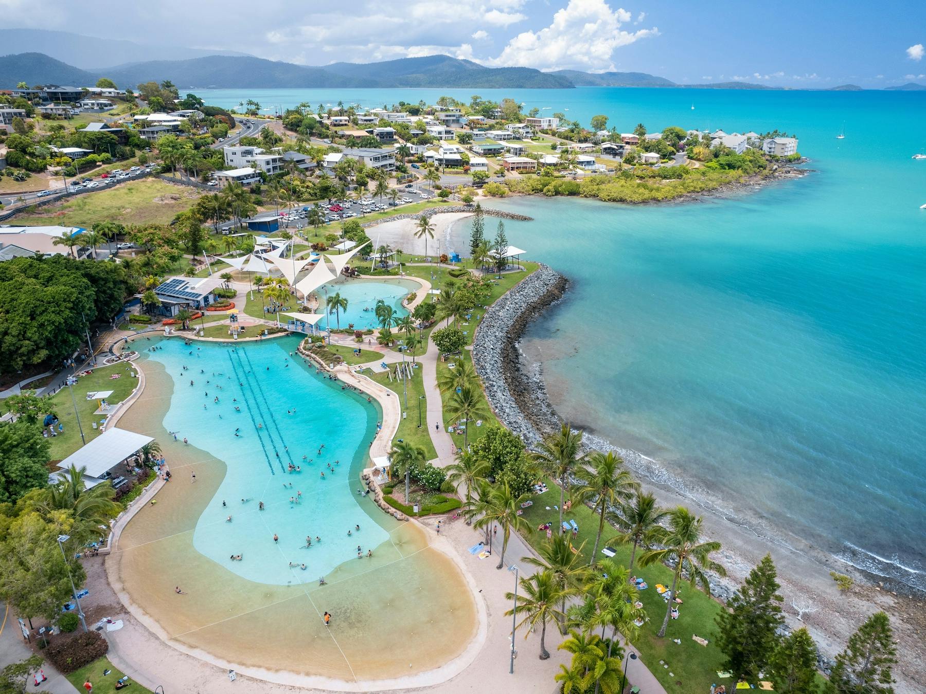 Aerial photo of Airlie Beach Lagoon with houses, beach and blue ocean surrounding