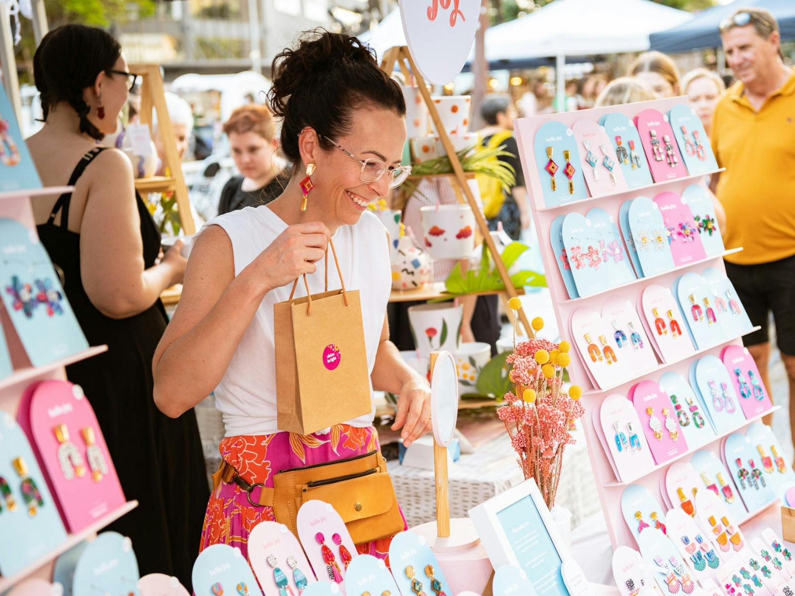 A Stallholder smiling while standing in her stall and holding a shopping bag