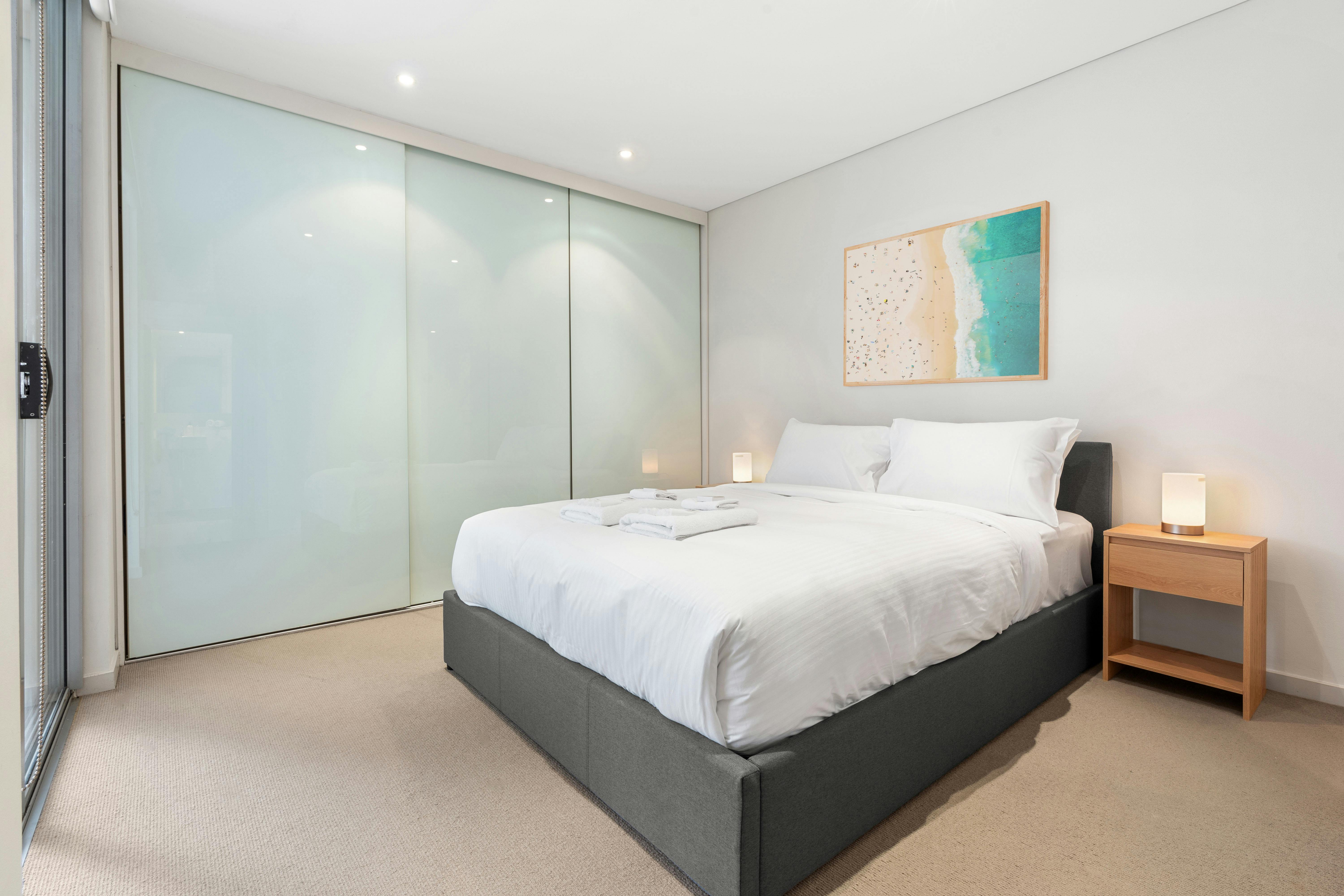 Bright bedroom with simple, modern furnishings and soft lighting.