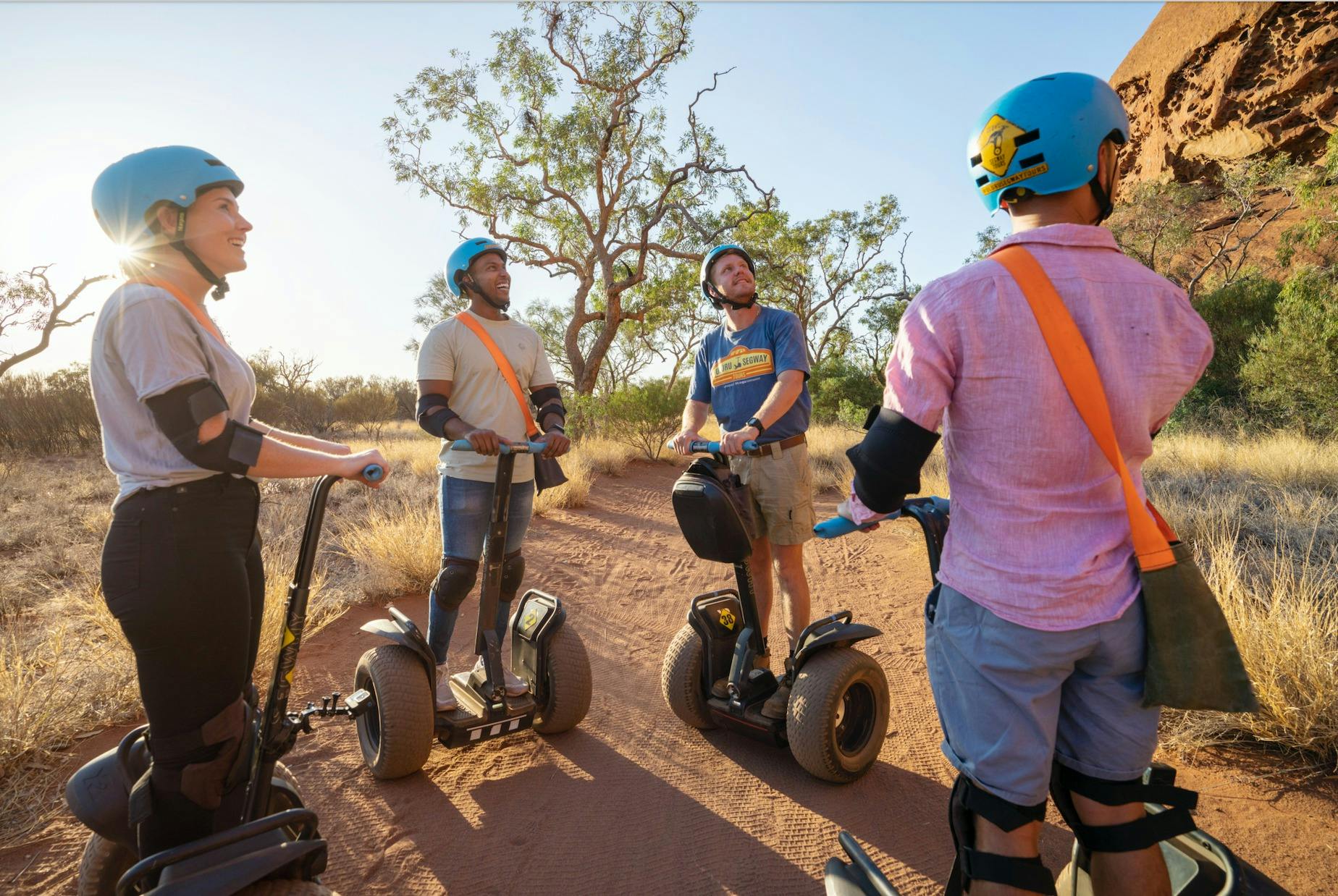 A group stop at the foot of Uluru and look up, marvelling at it's sheer size