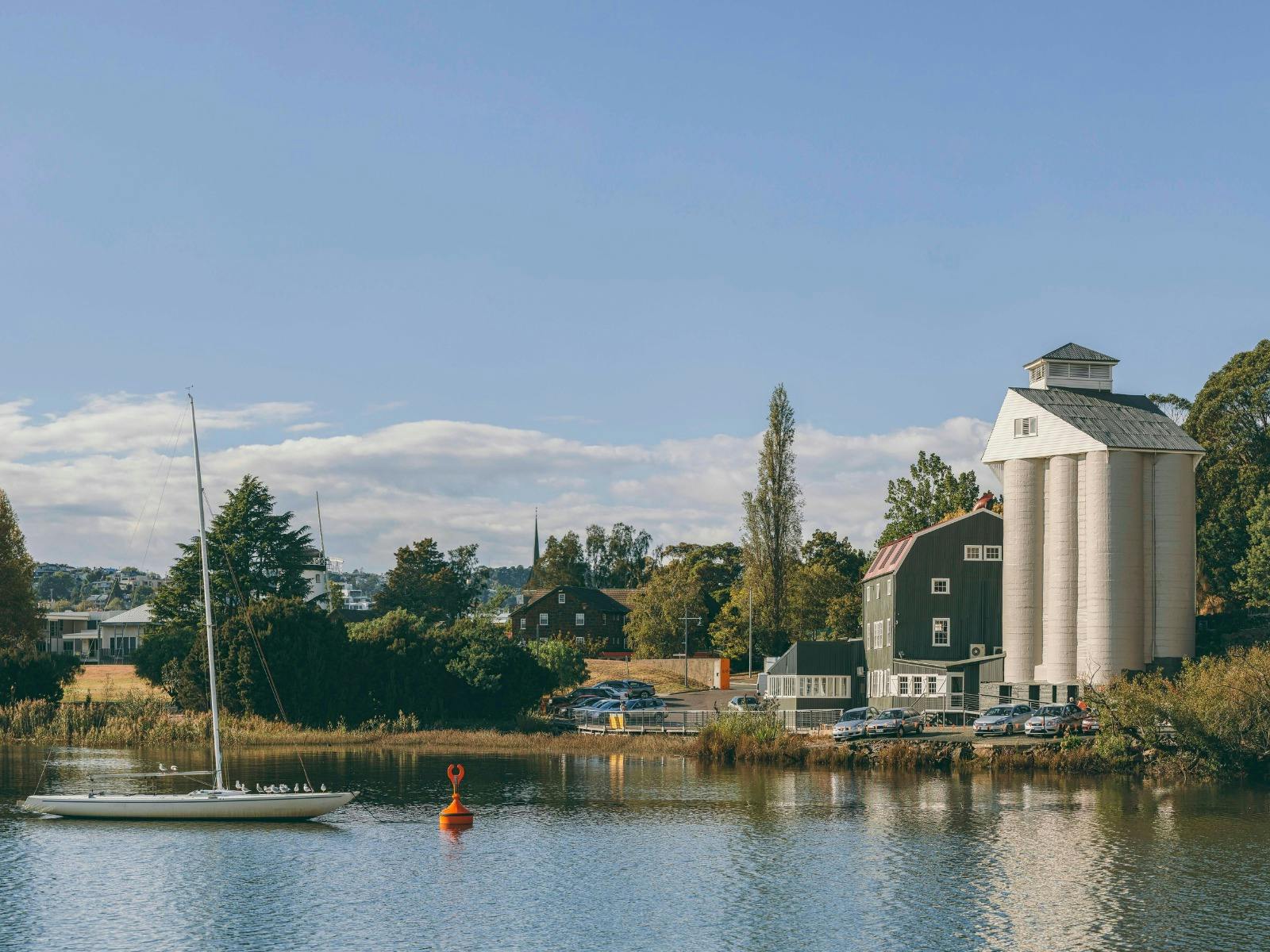 View from the water looking at an 1830's flour mill beside a calm estuary with a boat