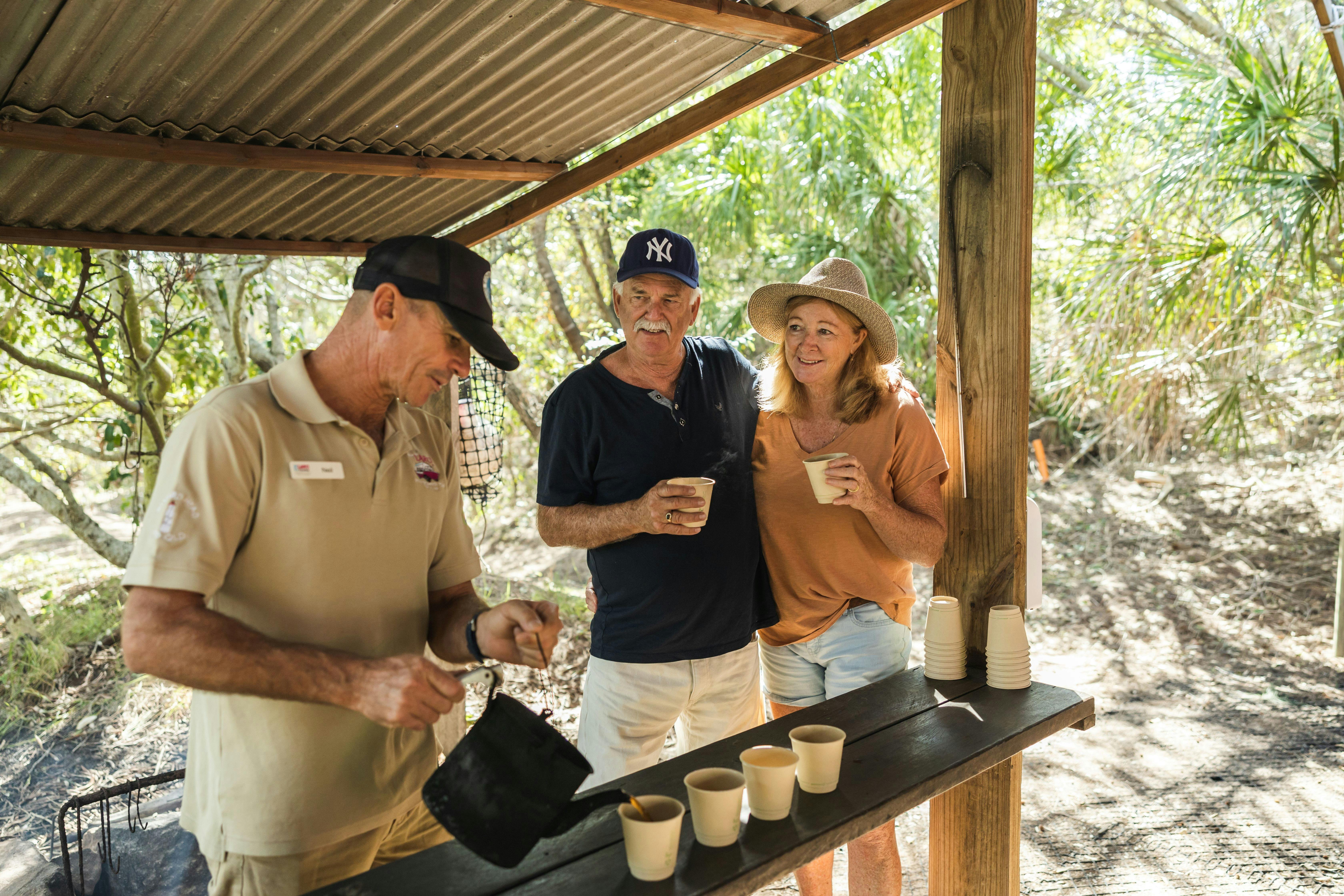 Guide pours a cup of freshly brewed billy tea for guests, at the shaded picnic area during lunch