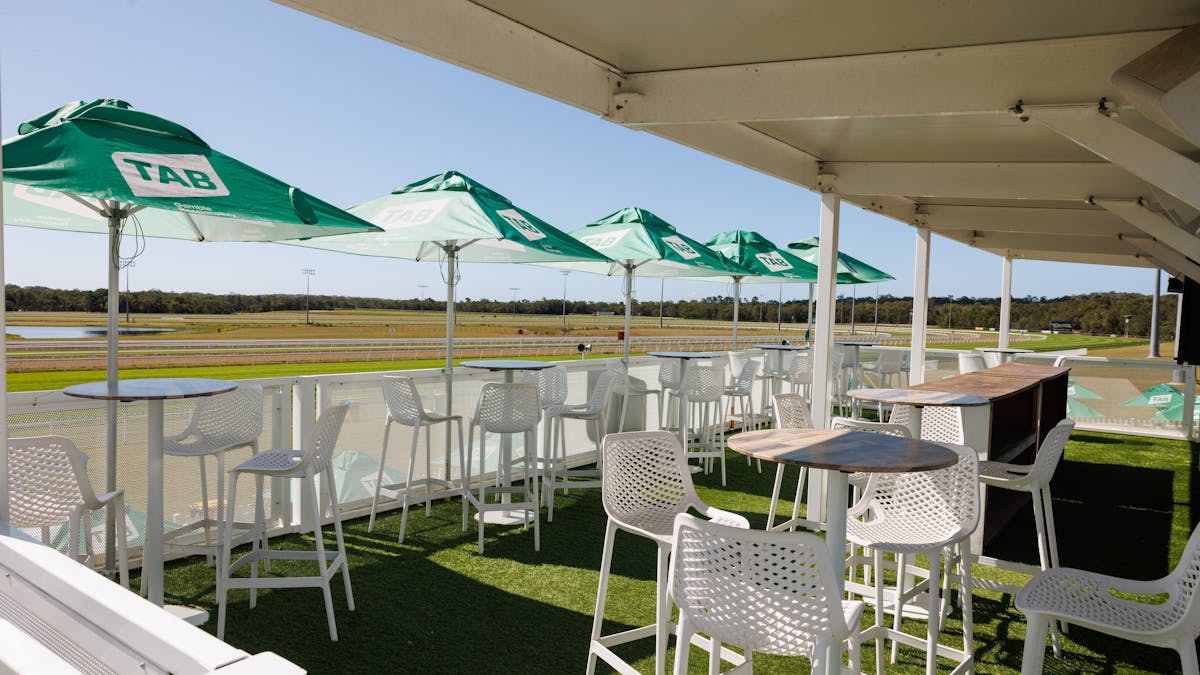Green TAB Branded umbrellas with high top tables overlooking the track