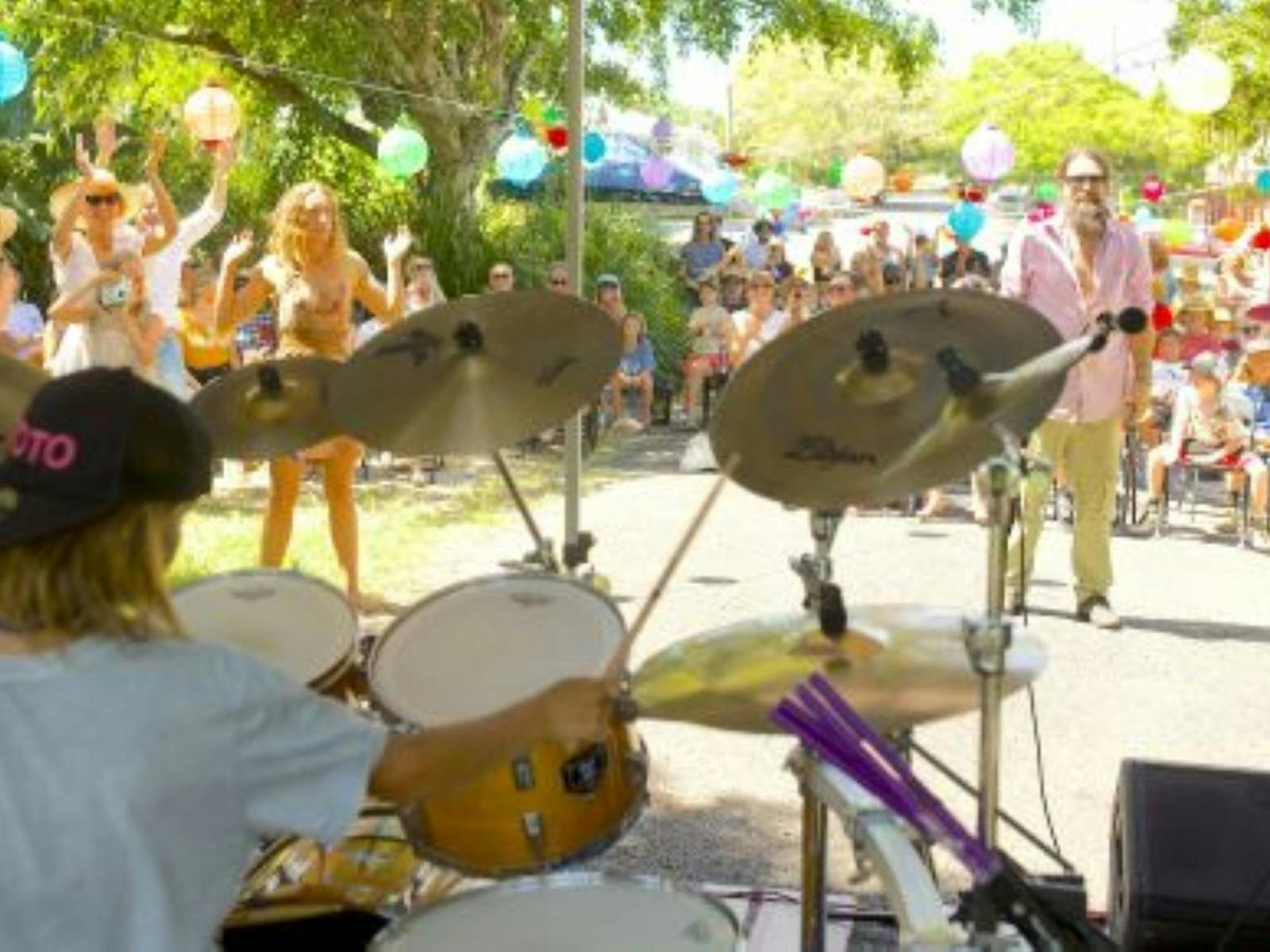 Image of a youth band performing on drums in front of a crowd of festival goers