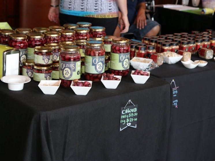 Table with bottled Olives, jars of spices and dishes with olives and spices in them for taste testing