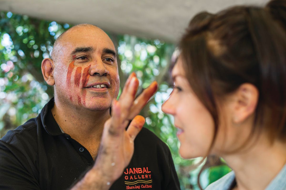 Artist painting a customer's face with natural ochre