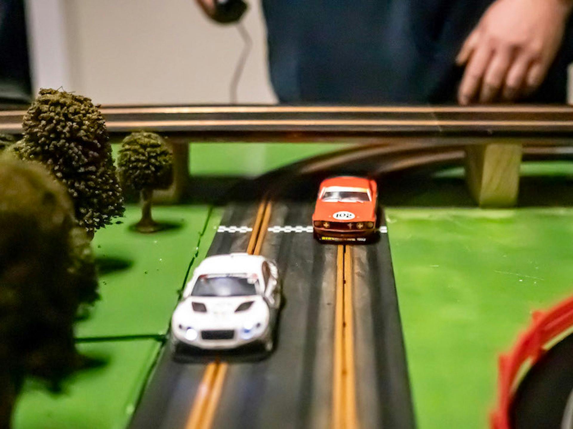 Two slot cars racing side by side toward the finish line.