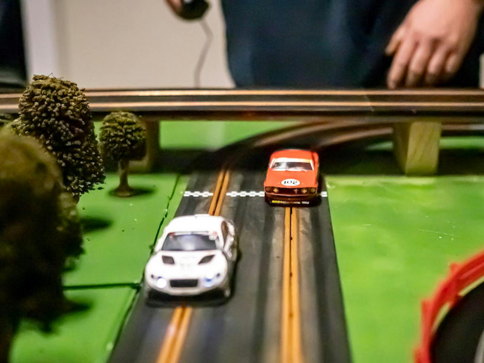 Two slot cars racing side by side toward the finish line.