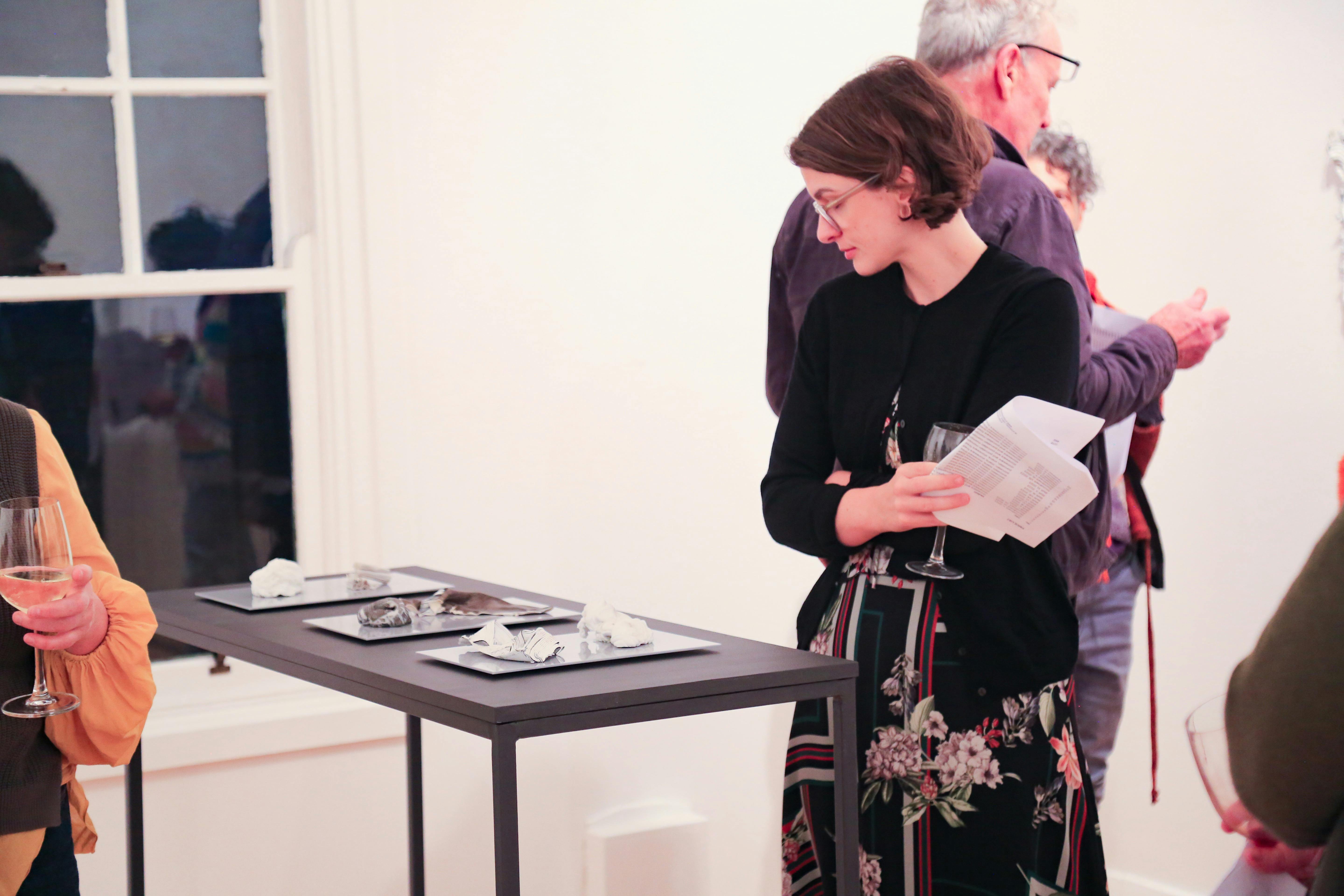 A woman looks at a plinth supporting ceramic artworks.