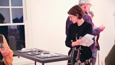 A woman looks at a plinth supporting ceramic artworks.