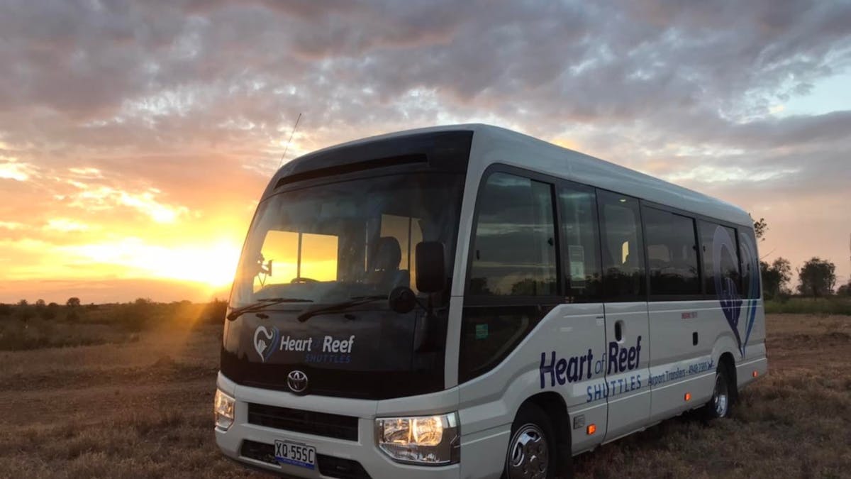 Heart of Reef Shuttles Bus in a field in front of a sunset