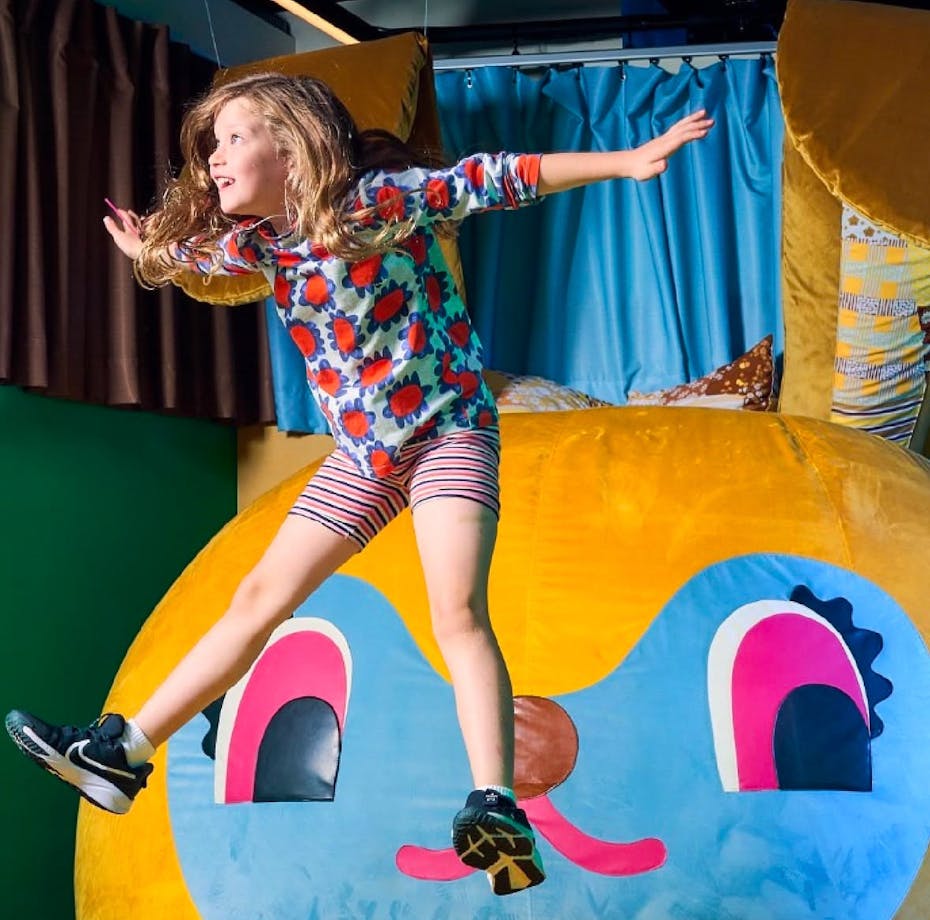 A girl jumps on Bunny Dearest by Beci Orpin. An interactive artwork.