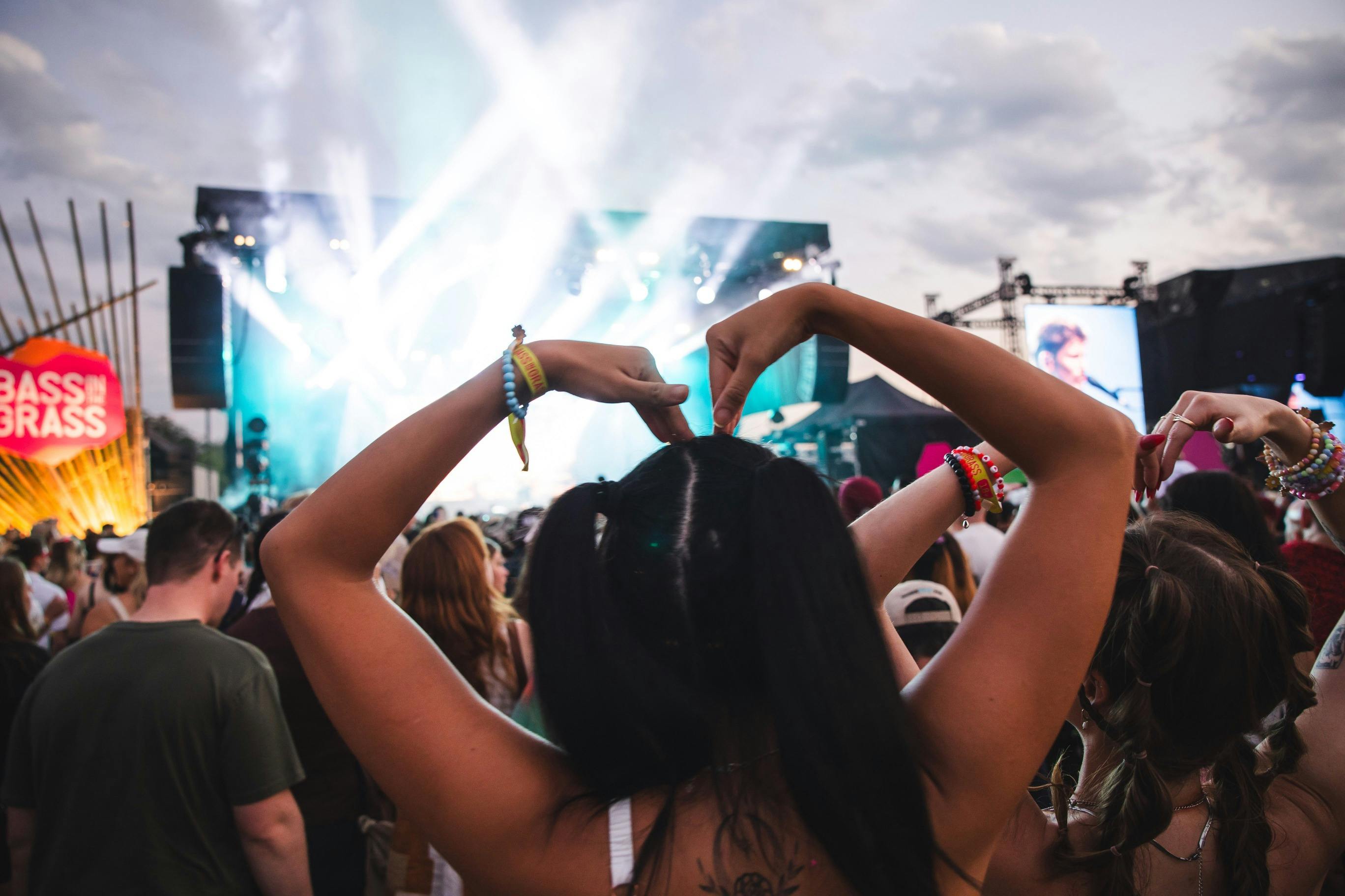 Crowd member at BASSINTHEGRASS 2024 making a loveheart with her arms