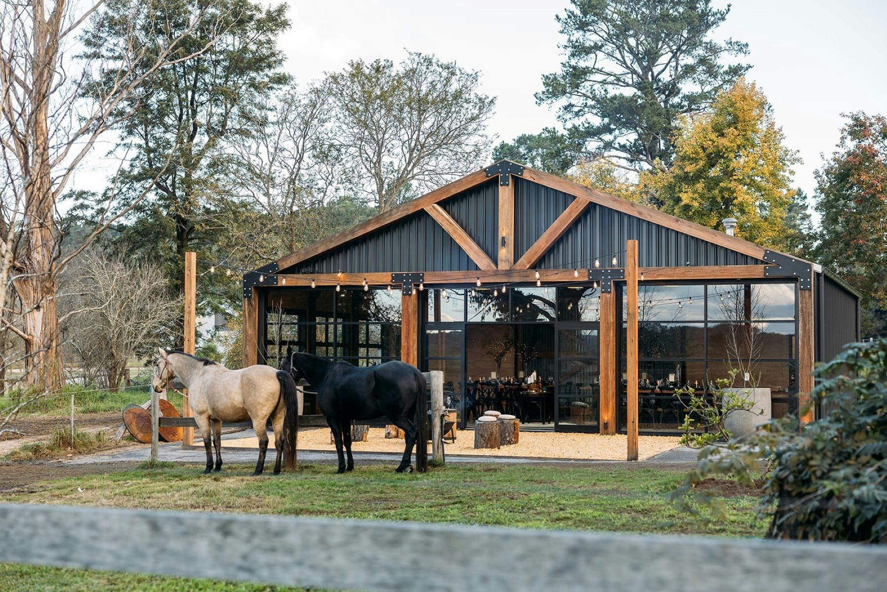 Front of stables event building in nature showing horses at the front and large glass windows light