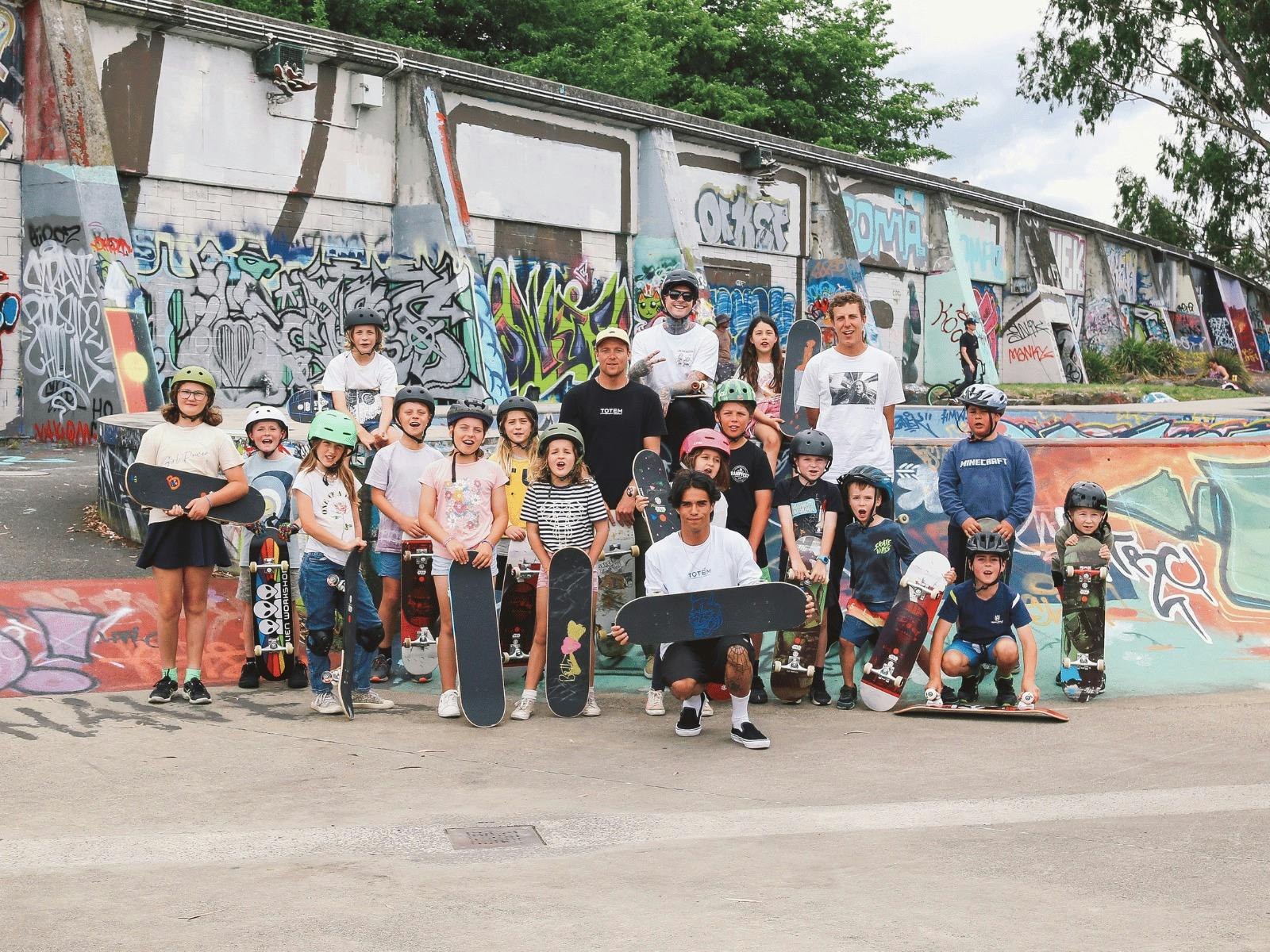 group of children and adults holding skateboards and posing for a group photo