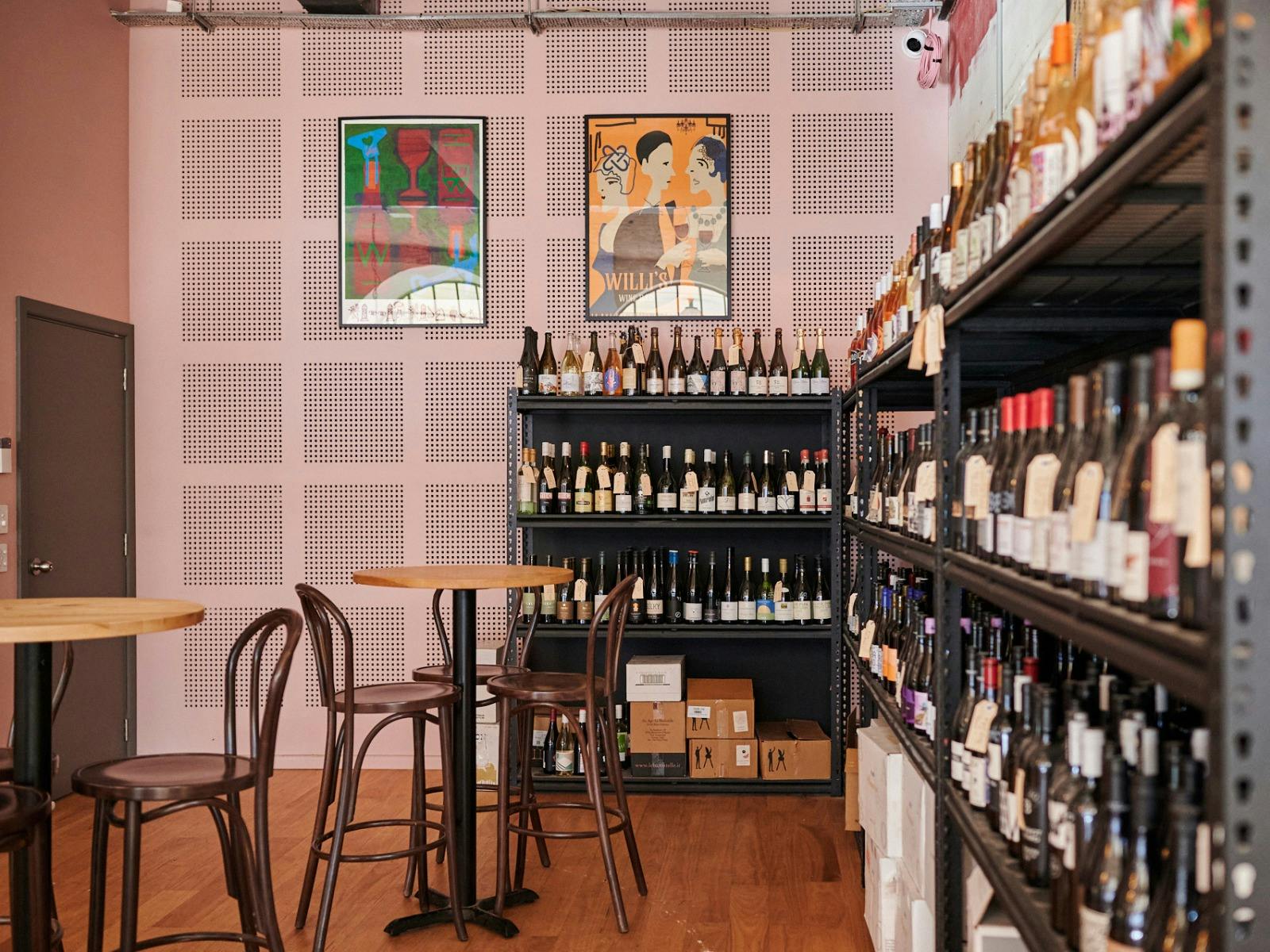 Tables and seating in front of wall shelf full of wines