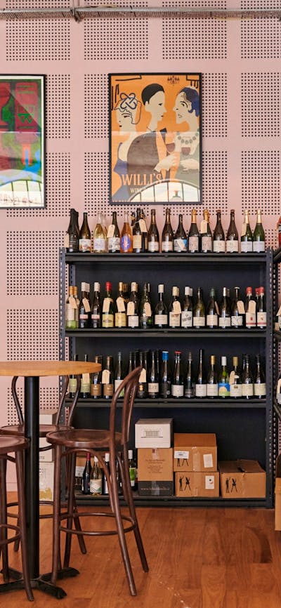 Tables and seating in front of wall shelf full of wines