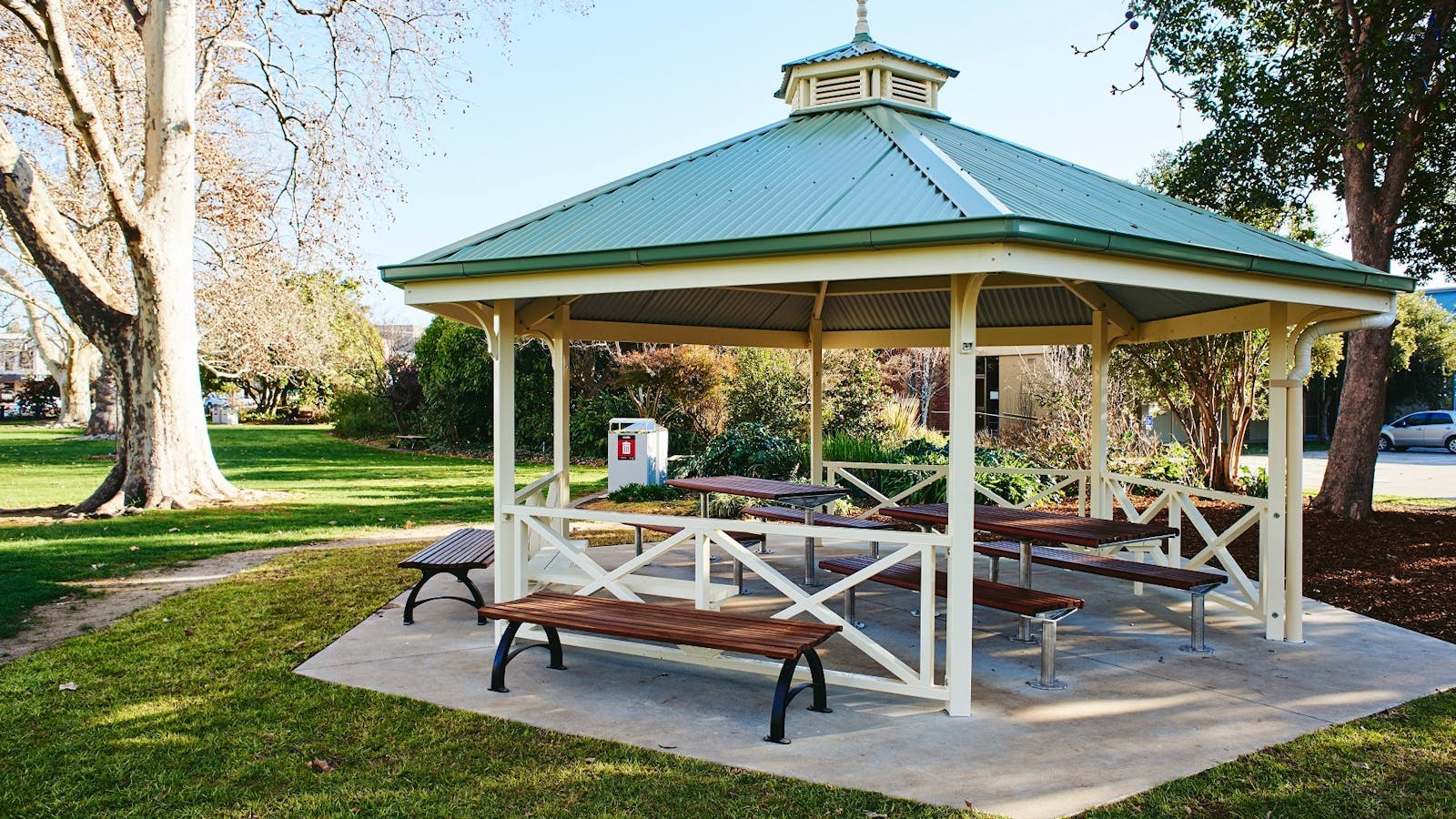 Rotunda, seats, picnic tables, grass, sunshine, trees, bushes