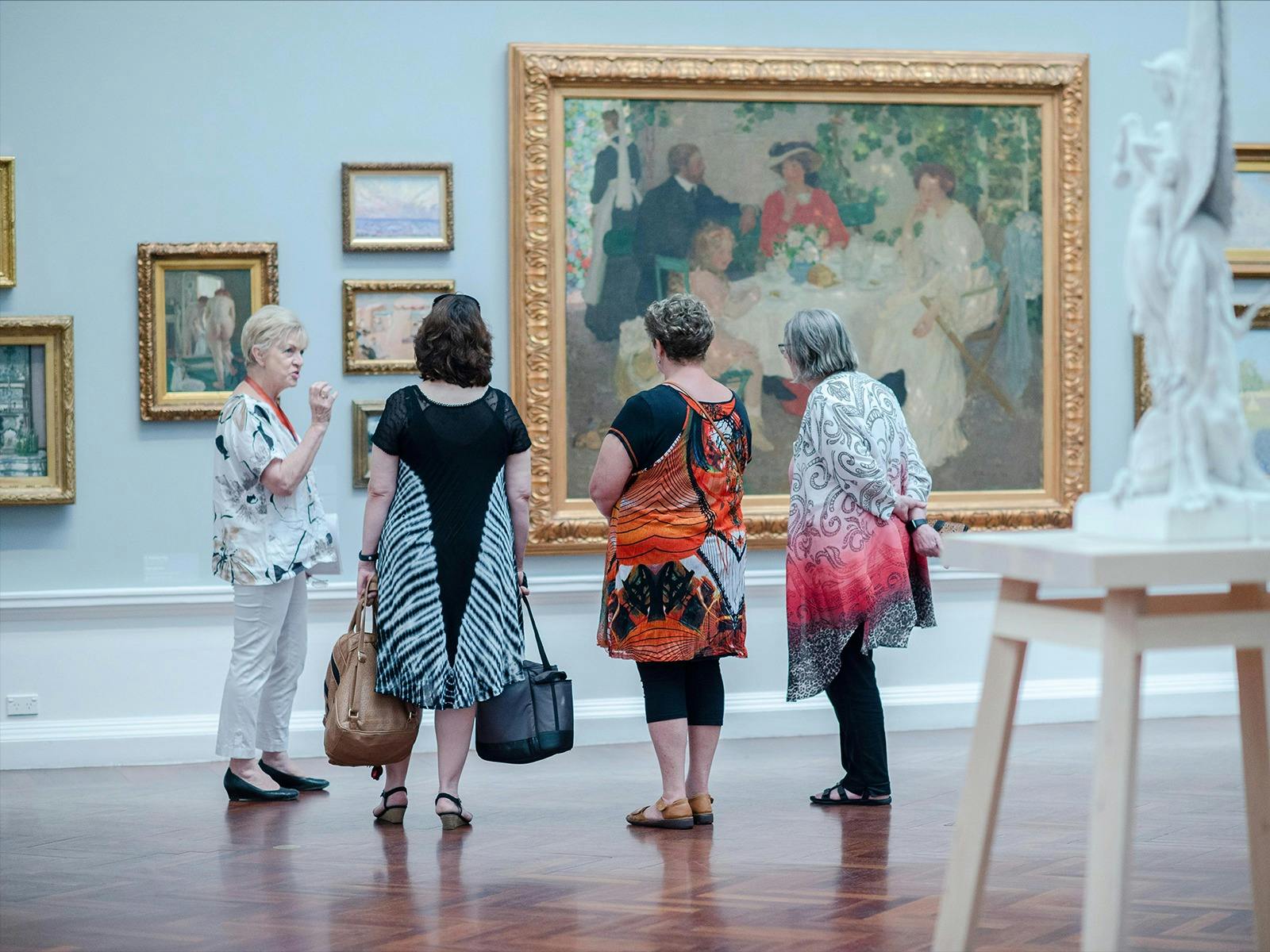 Image of tour guide speaking in front of art works