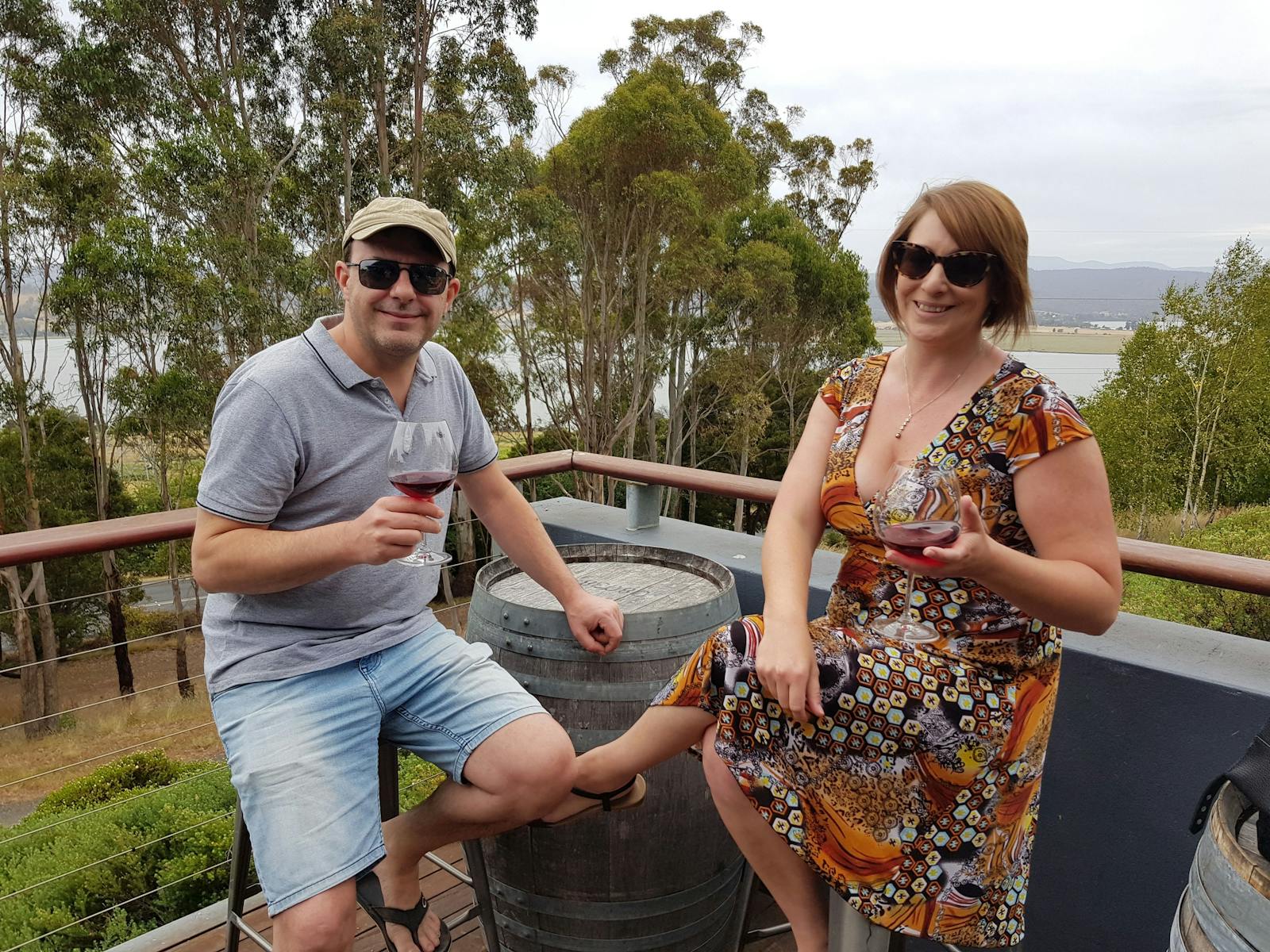 couple tasting wine on a balcony with Tamar River in background