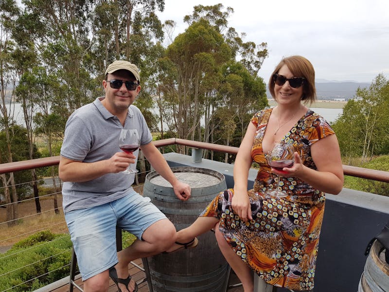 couple tasting wine on a balcony with Tamar River in background