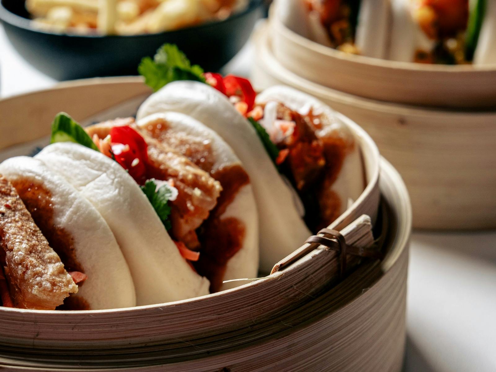 Close-up of three filled bao buns in a bamboo steamer.
