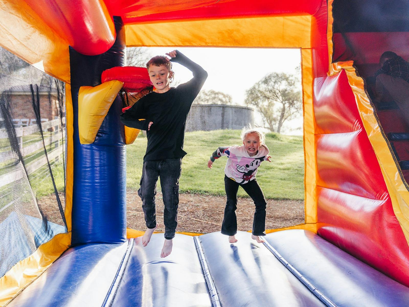 Two kids jumping in a jumping castle at Stockmans Ridge Wines
