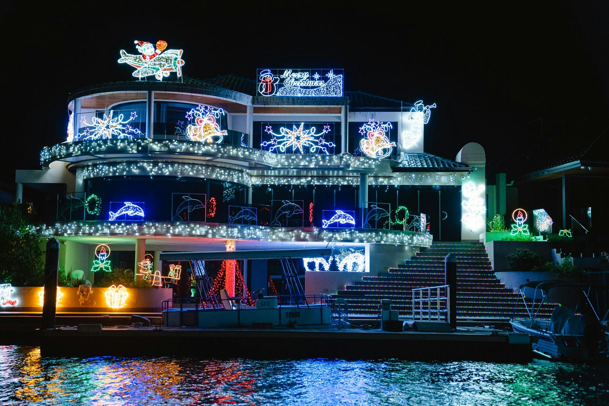 Waterfront mansion adorned with shimmering Christmas lights, reflecting beautifully on the canals.