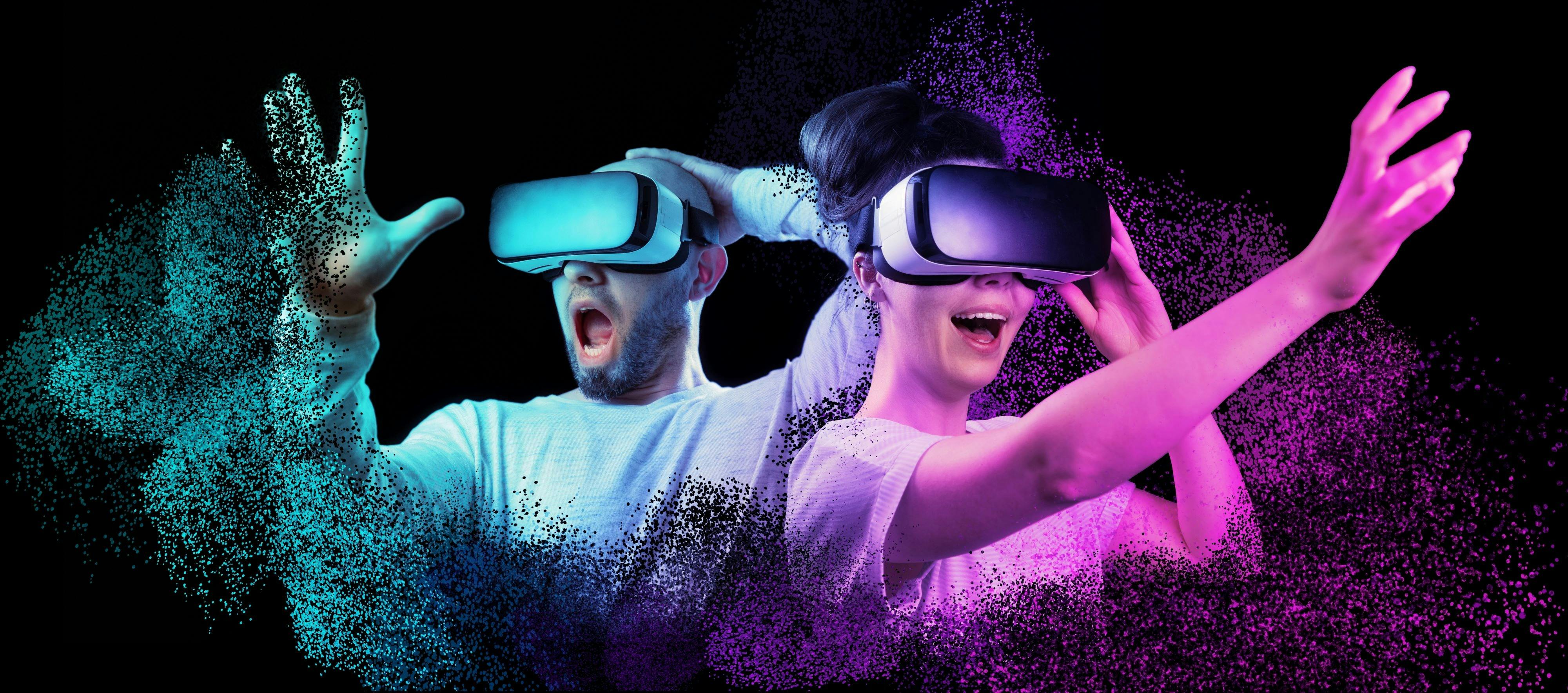 A man and woman both with VR headsets on reaching out in amazement.