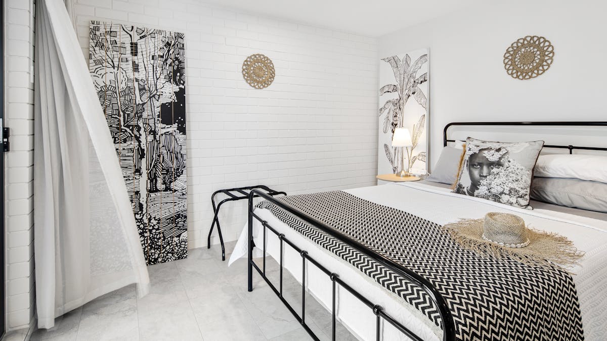 interior, queen bed, pillows and two painted doors leaning against the wall,