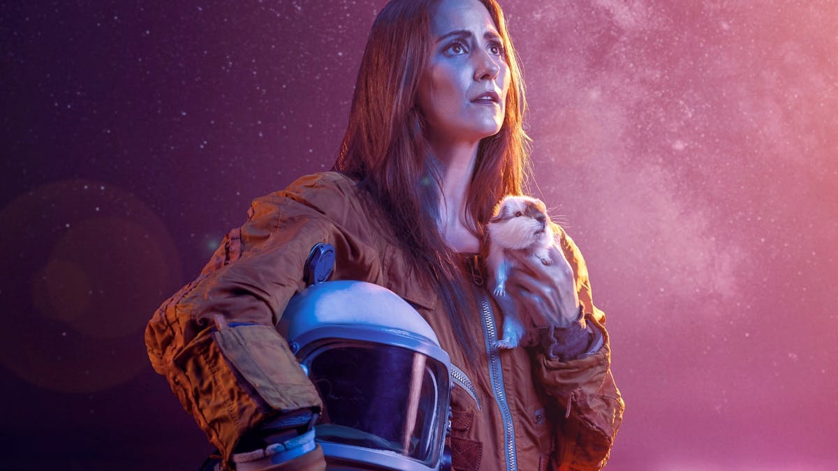 Women in a spacesuit looking in to the distance while holding a guinea pig