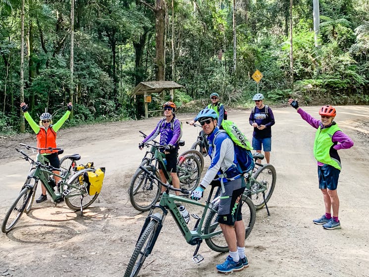 Group of riders with hands in air stopped for a rest before climbing hill into National Park