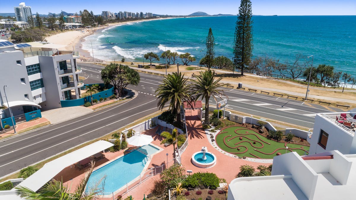 Aerial image of the pool and grounds of Alexandria Apartments and the ocean in the background