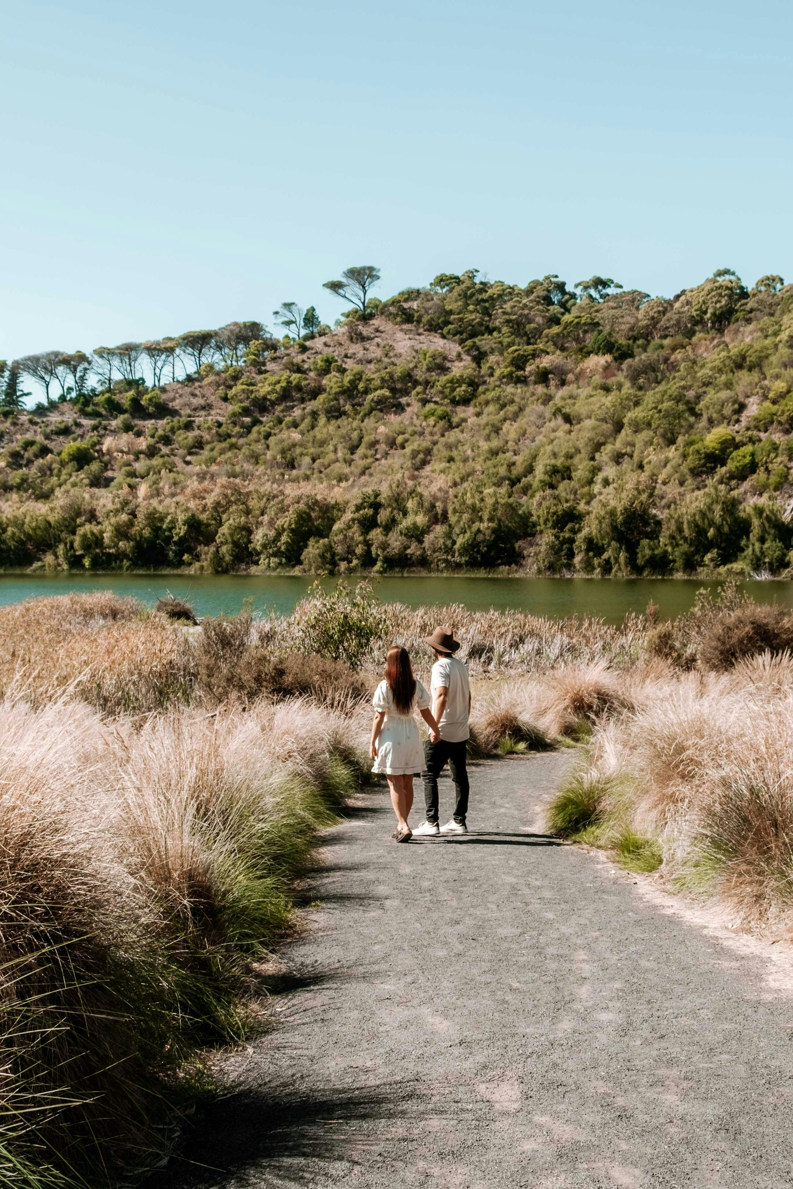 couple walking on a trail towards lake