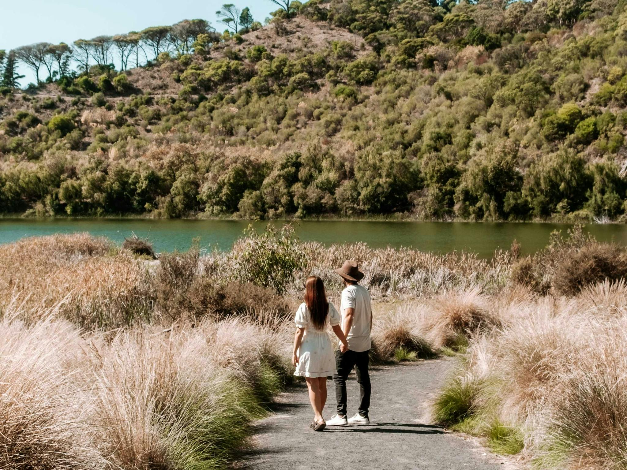 couple walking on a trail towards lake
