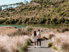 couple walking on a trail towards lake