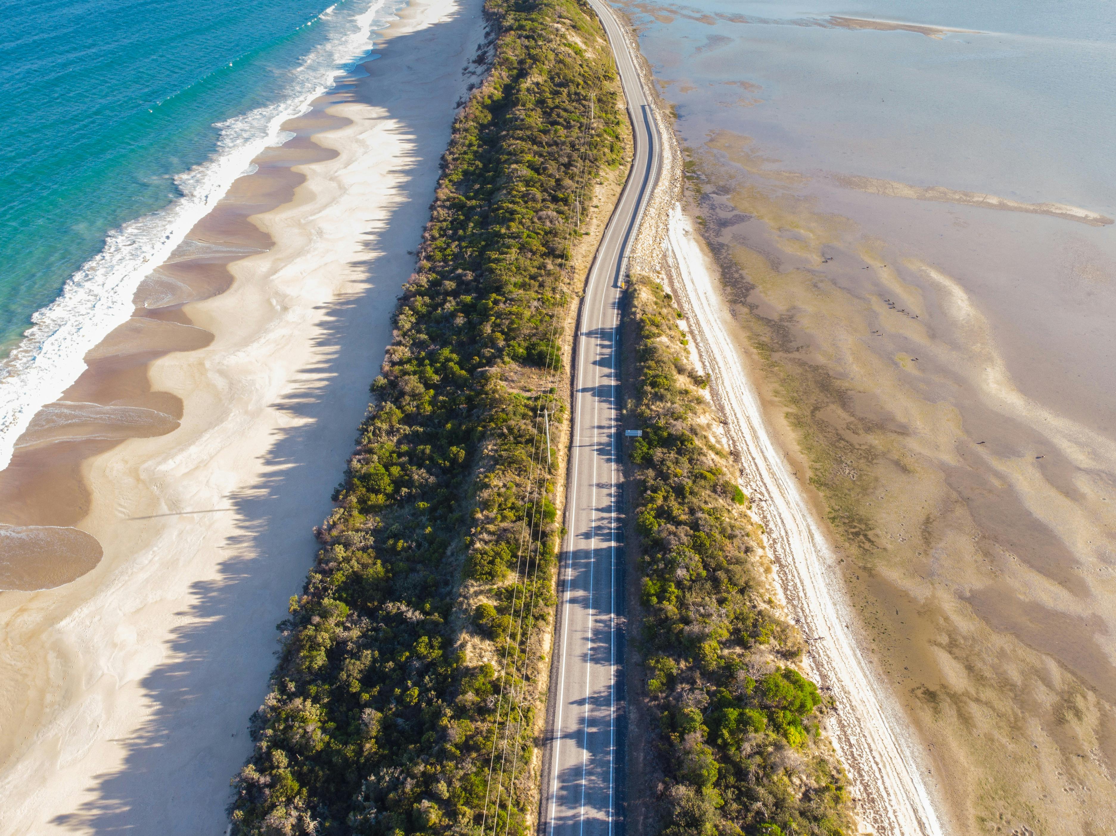 A sun-drenched road with white sand beaches on each side.