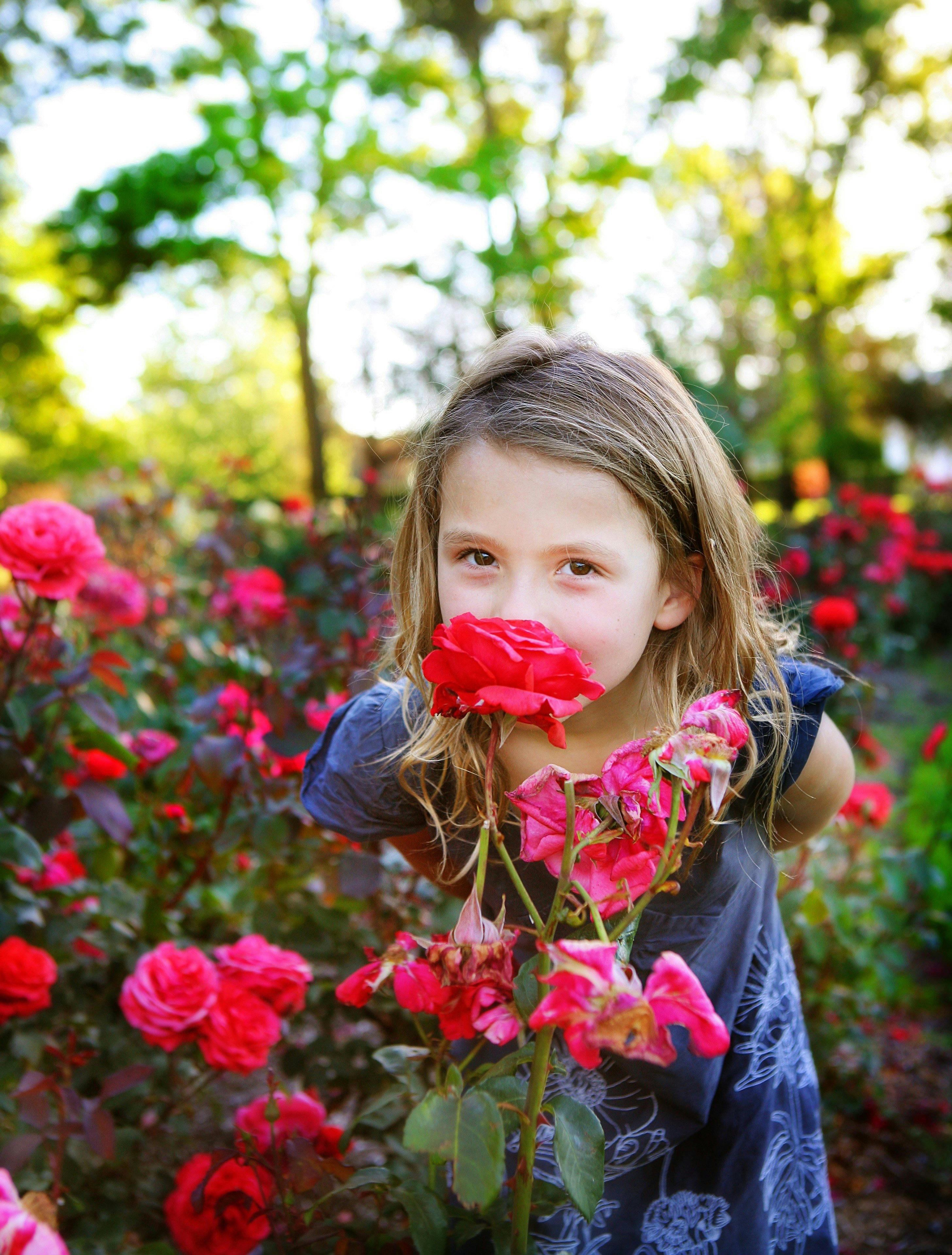 Young girl smelling roses. Photo by Jinkyart